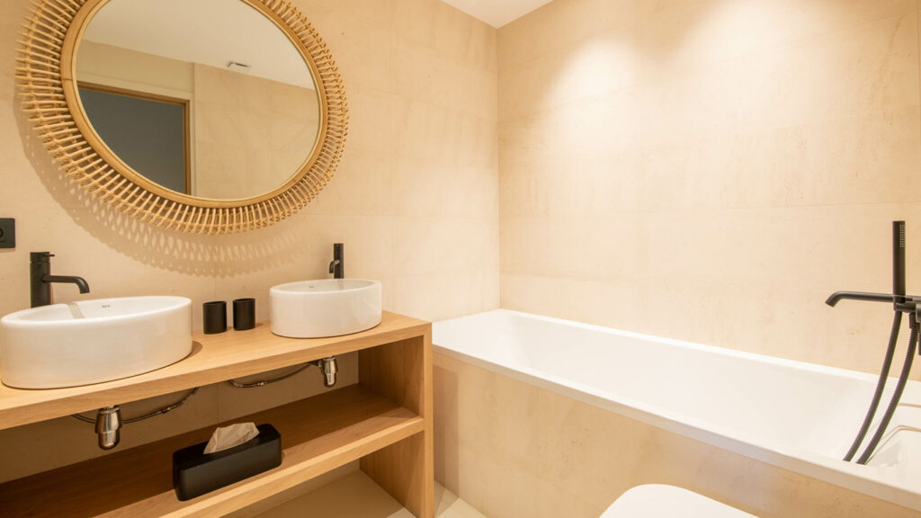 Aperçu de la salle de bain créée dans le projet de suite parentale : baignoire et meuble double vasques posées sur un plan de toilette en bois, murs en tadelakt