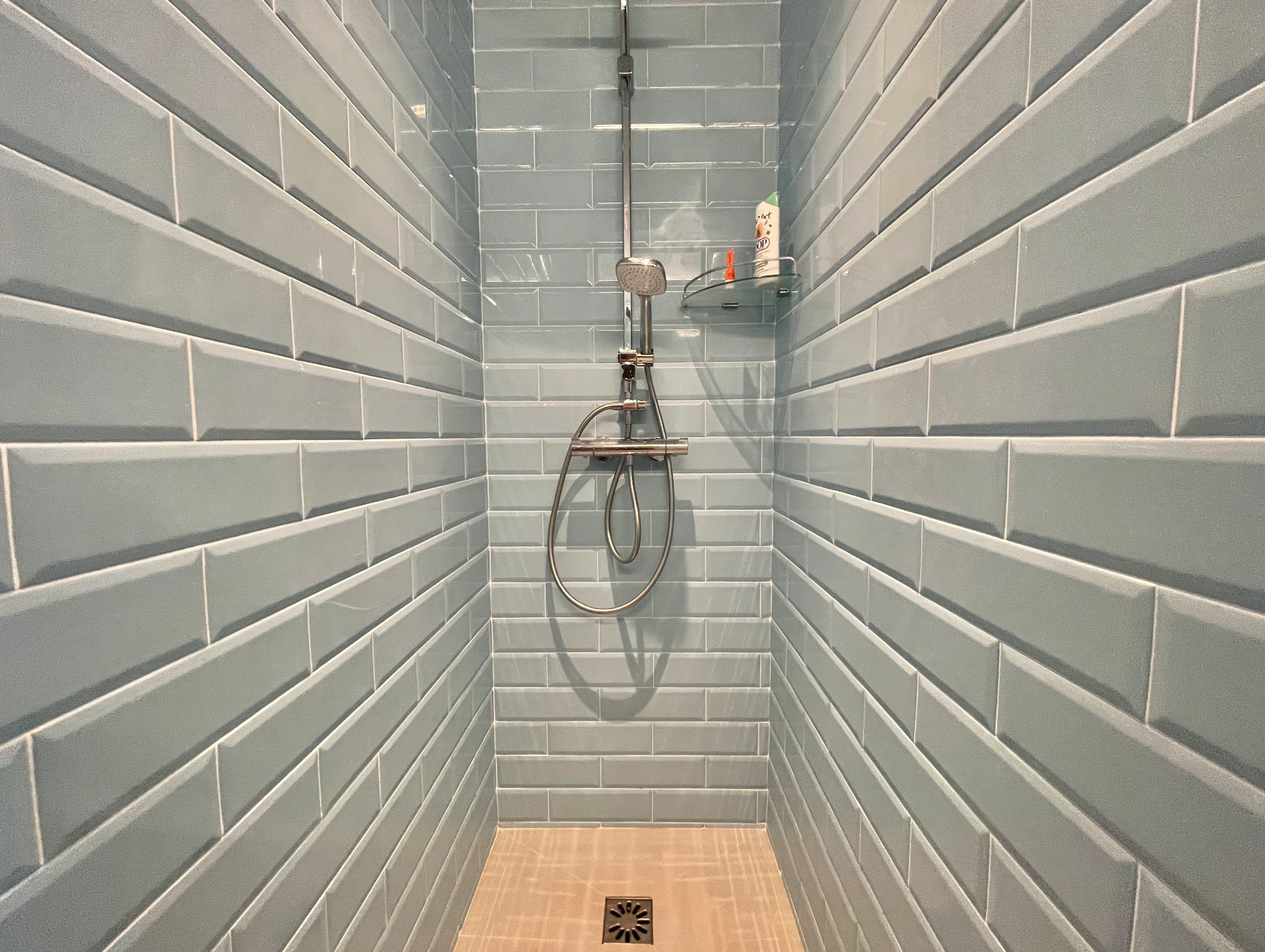 Rénovation d'une douche, détail du carrelage style métro dans une teinte bleu ciel