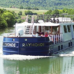 péniche sur le fleuve. Elles est bleue et présente sa terrasse. péniche croisieurope aménagée par Marine Giorgetti architecte d'intérieur